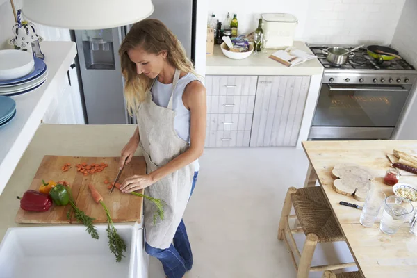 Kvinne på kjøkkenet som hogger grønnsaker – stockfoto