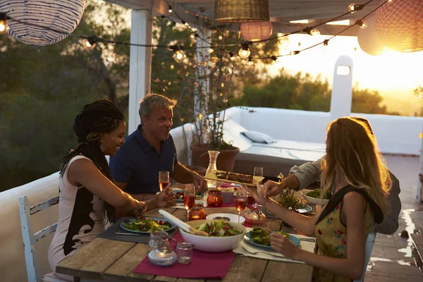 Two couples eating dinner at sunset — Stock Photo, Image