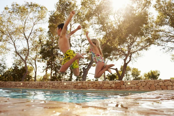 Visão traseira de crianças pulando na piscina — Fotografia de Stock
