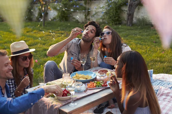 Amici che soffiano bolle al picnic — Foto Stock