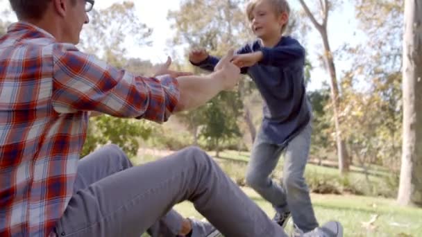 Vader en zoon spelen in een park — Stockvideo