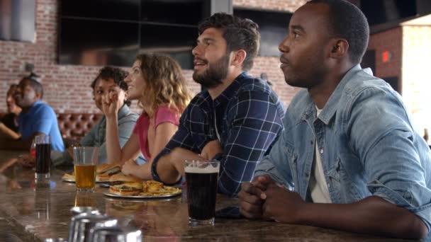 Amigos assistindo jogo na barra de esportes — Vídeo de Stock