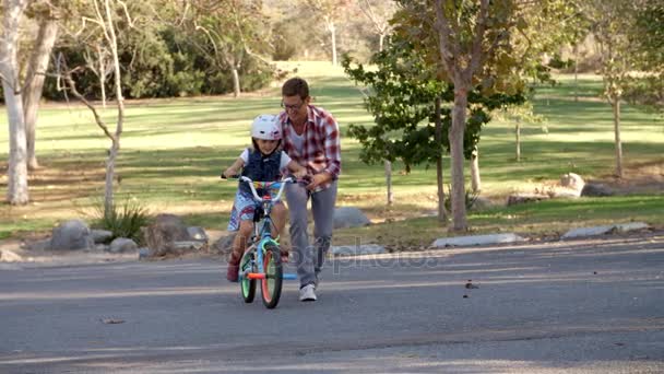 Father teaching daughter to ride a bike — Stock Video