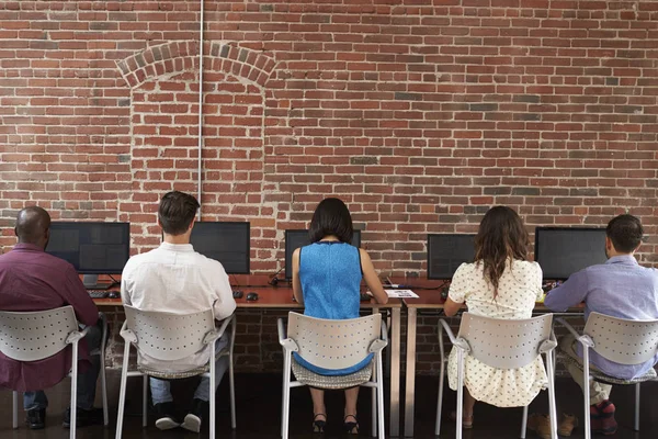 Vista trasera del personal en los escritorios usando computadoras en oficinas ocupadas —  Fotos de Stock