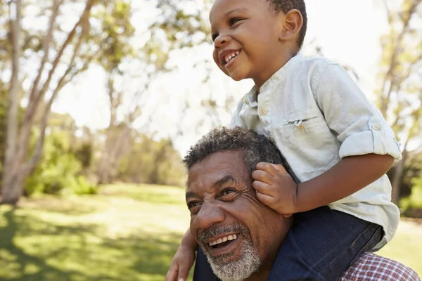 Grand-père porte petit-fils sur les épaules — Photo