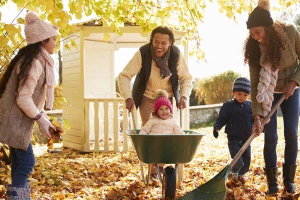 Barn hjälper föräldrar att samla löv — Stockfoto