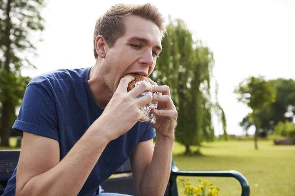 Genç adam yeme hamburger — Stok fotoğraf