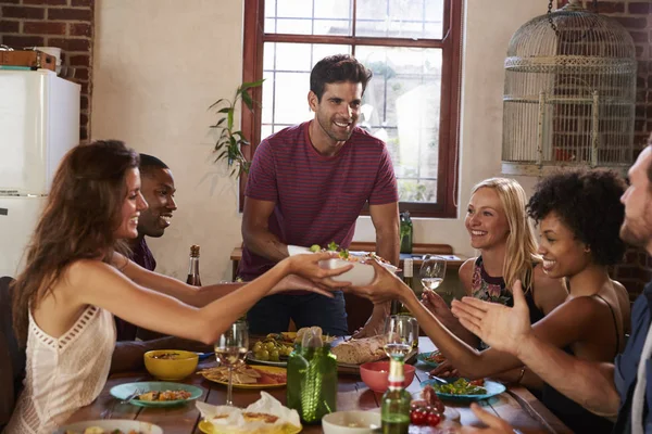 Amigos pasan comida alrededor de la mesa —  Fotos de Stock