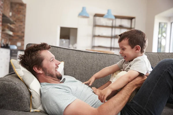 Отец и сын обнимаются на диване — стоковое фото