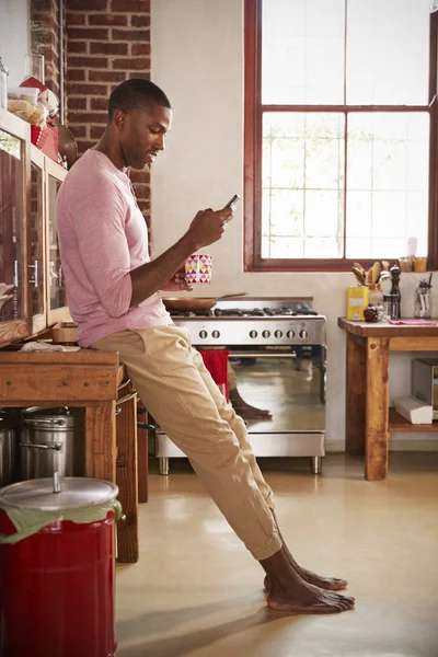Uomo utilizzando smartphone in cucina — Foto Stock
