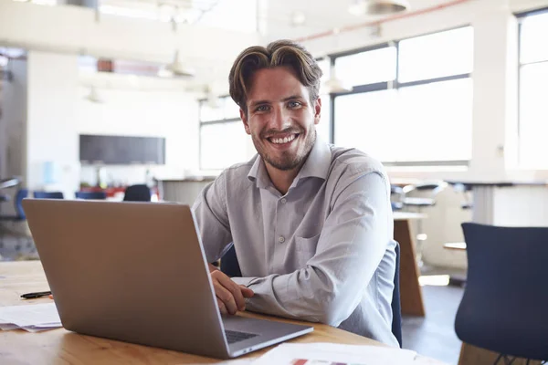 Young man in office using laptop — Stock Photo, Image