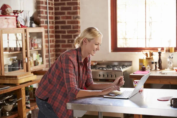 Woman using computer in kitchen — Stock Photo, Image