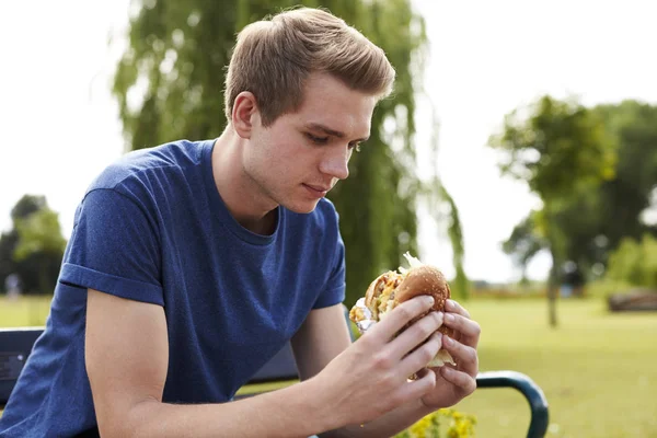 若い男が食べるハンバーガー — ストック写真