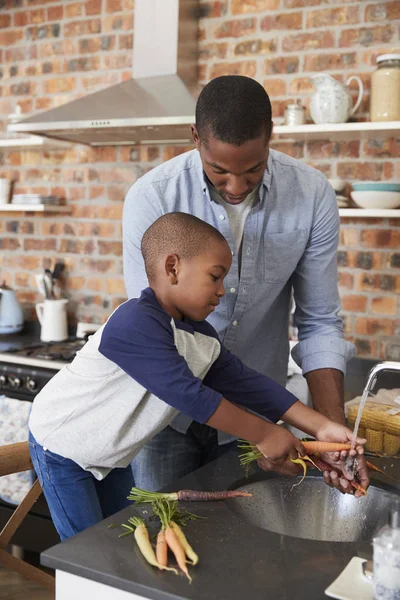 Filho ajudando o pai a preparar legumes — Fotografia de Stock