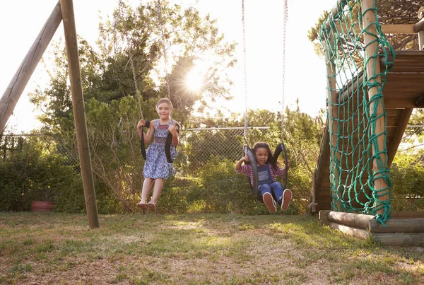 Meisjes spelen op tuin schommels — Stockfoto