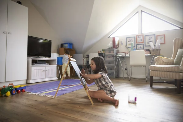 Mädchen zeichnet auf Kreidetafel im Spielzimmer — Stockfoto