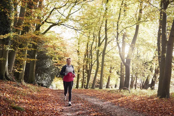 Kobieta działa poprzez jesień Woodland — Zdjęcie stockowe