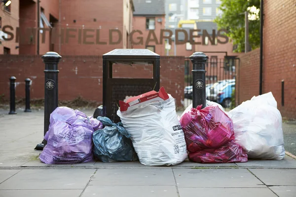 Sacos de basura apilados junto a la papelera — Foto de Stock