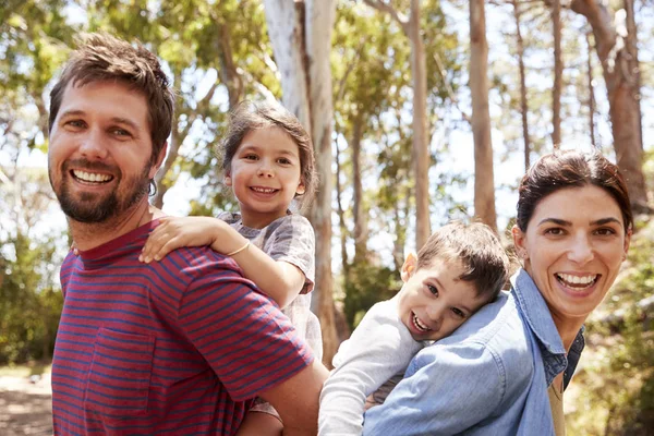 Sonriente pareja piggybacking niños — Foto de Stock