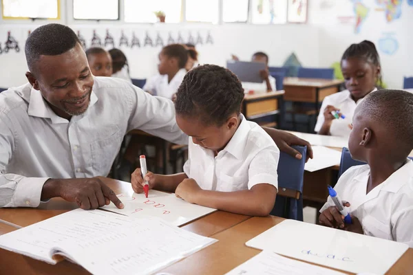 Teacher helping girl at desk — Stock Photo, Image