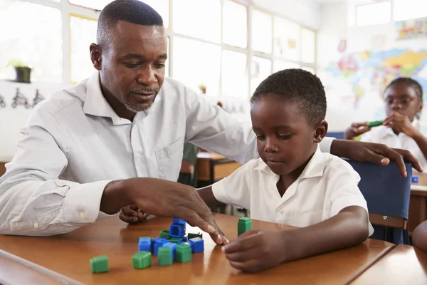 Nauczyciel pomaga chłopiec liczenia z bloków — Zdjęcie stockowe