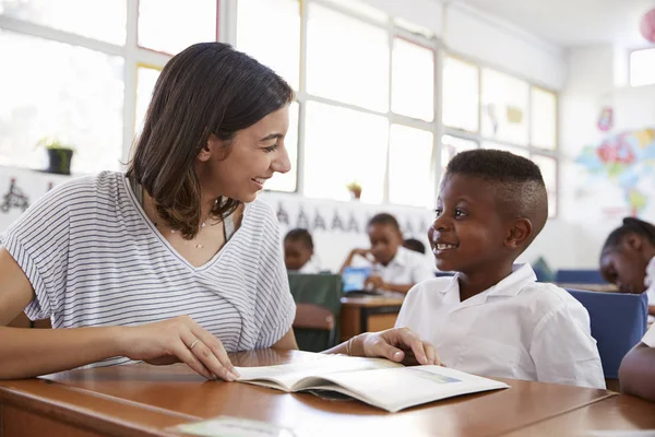 Profesor ayudando a colegial en escritorio — Foto de Stock