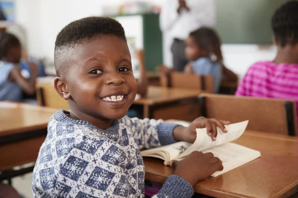 Ragazzo alla scrivania sorridente alla macchina fotografica — Foto Stock