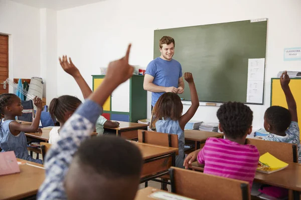 Bambini alzando le mani in classe scolastica — Foto Stock
