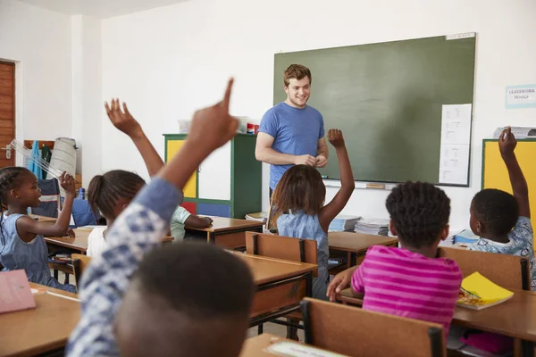 Niños levantando las manos en clase escolar — Foto de Stock