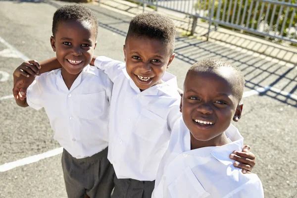 Skolpojkar leende till kamera på lekplats — Stockfoto