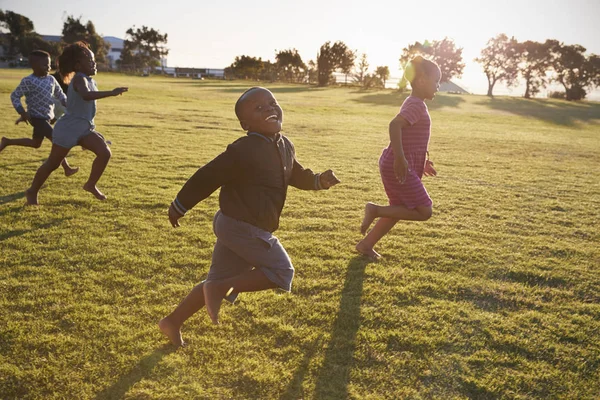 Meninos e meninas da escola correndo no campo — Fotografia de Stock