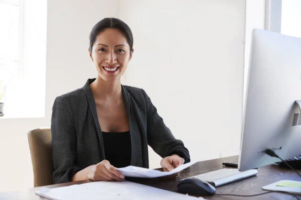 Woman at desk holding documents — Stock Photo, Image