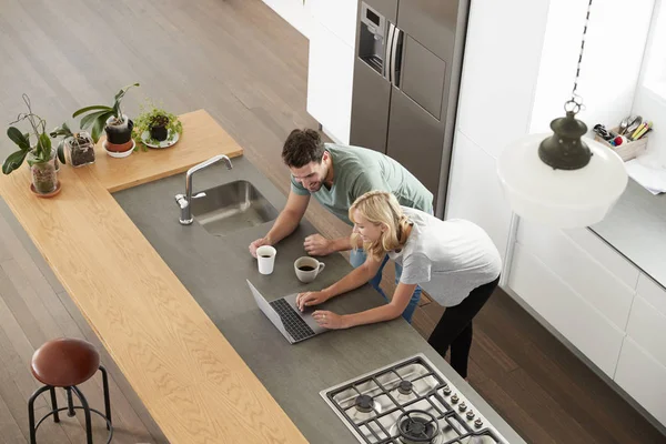 Pareja mirando portátil en la cocina — Foto de Stock