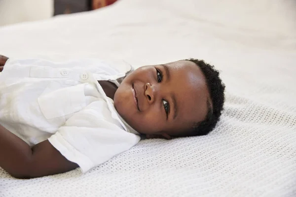 Sonriente joven acostado en la cama — Foto de Stock