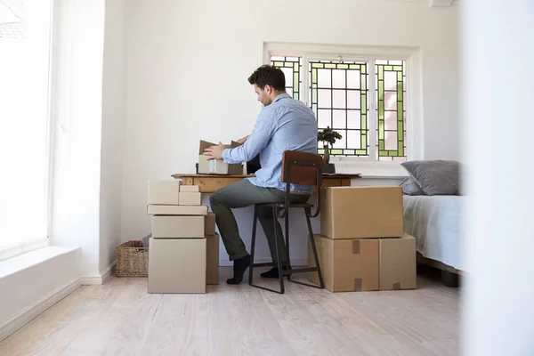 Homem sentado à mesa com caixas — Fotografia de Stock