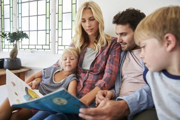 Семья с детьми читает книгу — стоковое фото