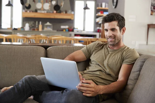 Людина на вітальні диван за допомогою ноутбука — стокове фото