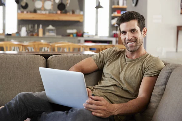 Mann auf Lounge-Sofa mit Laptop — Stockfoto