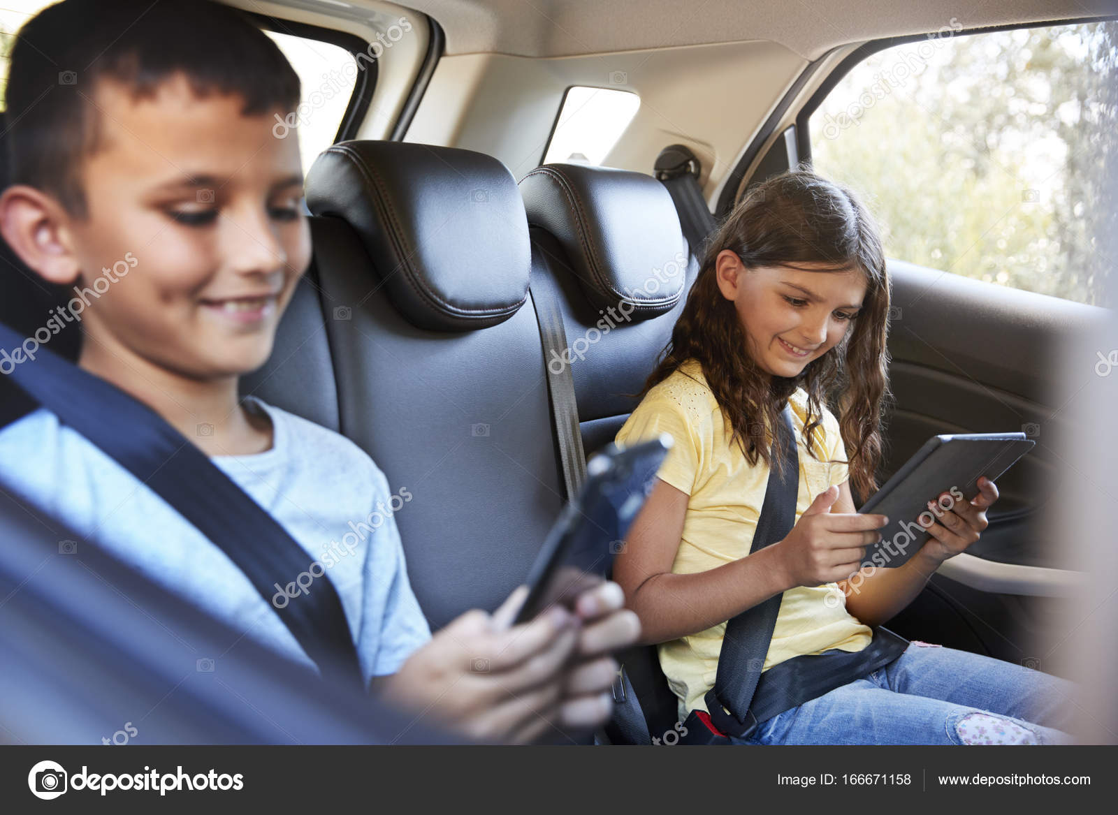boy and girl in car using tablets stock photo monkeybusiness