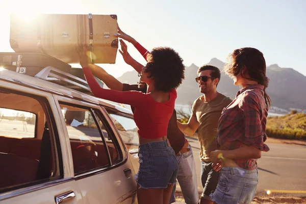 Amigos cargando equipaje en el techo del coche — Foto de Stock