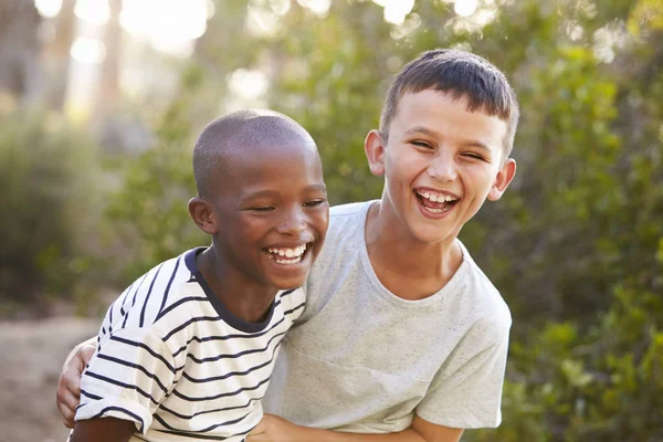 Retrato de dois meninos abraçando e rindo ao ar livre — Fotografia de Stock