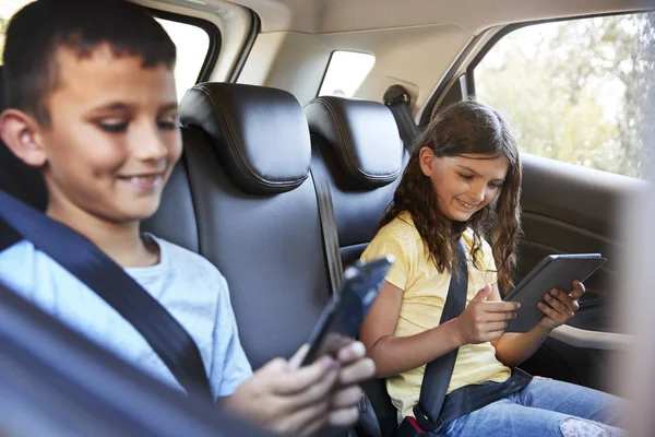 Menino e menina no carro usando tablets — Fotografia de Stock