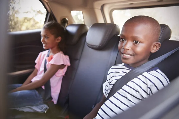 Улыбающаяся девочка и мальчик на заднем сиденье машины — стоковое фото