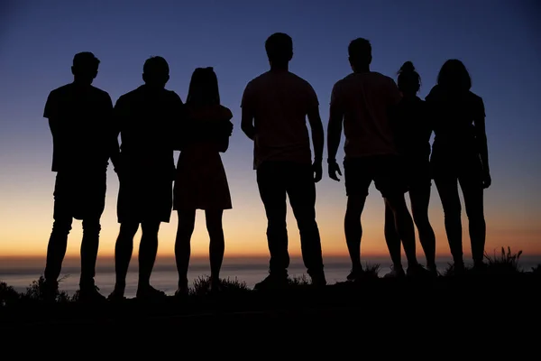 Adulti ammirando il tramonto in riva al mare — Foto Stock