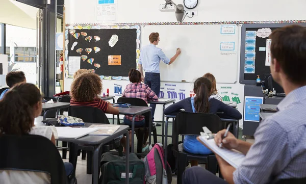 Insegnante tirocinante che scrive alla scrivania della scuola — Foto Stock