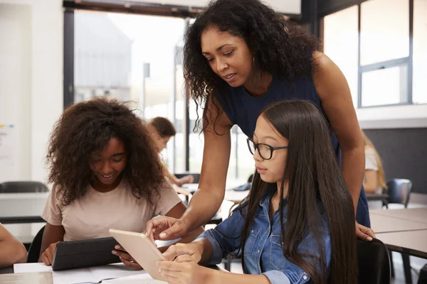 Teacher helping students with tablet