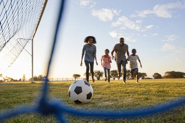 Famiglia nera che corre dietro al calcio Immagine Stock