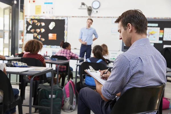 Trainee teacher writing at school desk — Stock Photo, Image