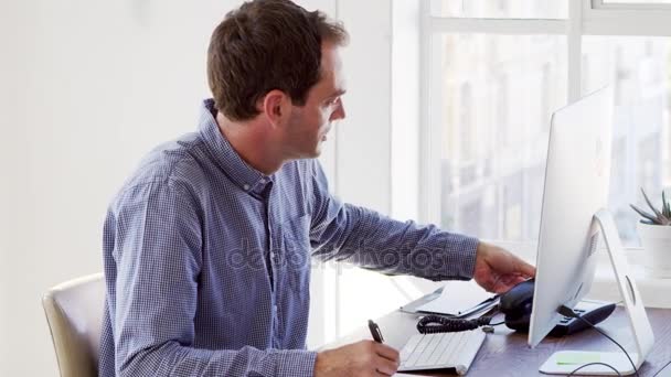 Человек с помощью телефона и компьютера в офисе — стоковое видео