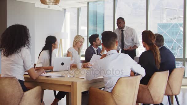 Hombre de negocios dirigiendo la reunión alrededor de la mesa — Vídeos de Stock